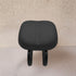 Black stool with cushioned seat on a beige background
