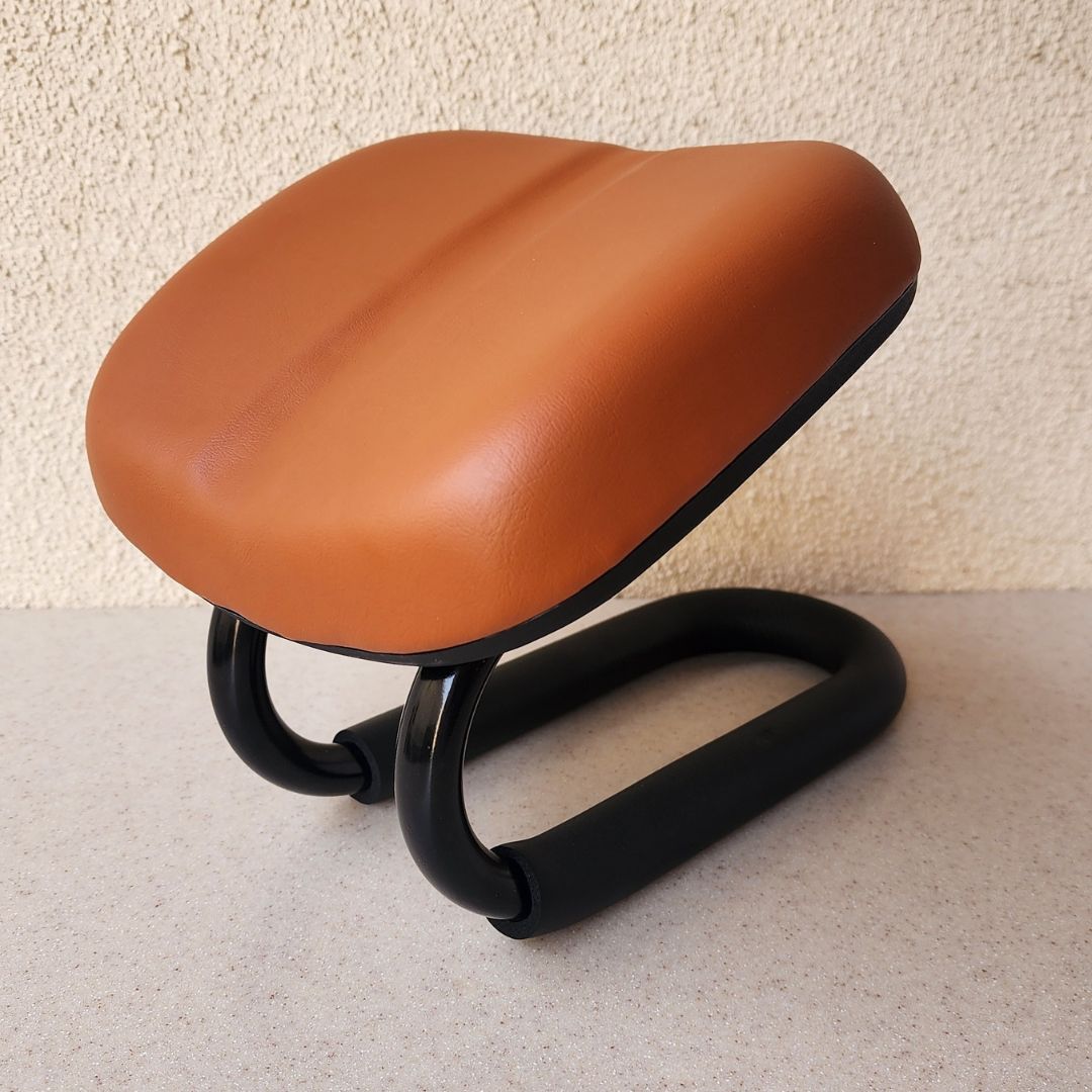 Brown saddle-like object on a black metal frame against a beige wall.