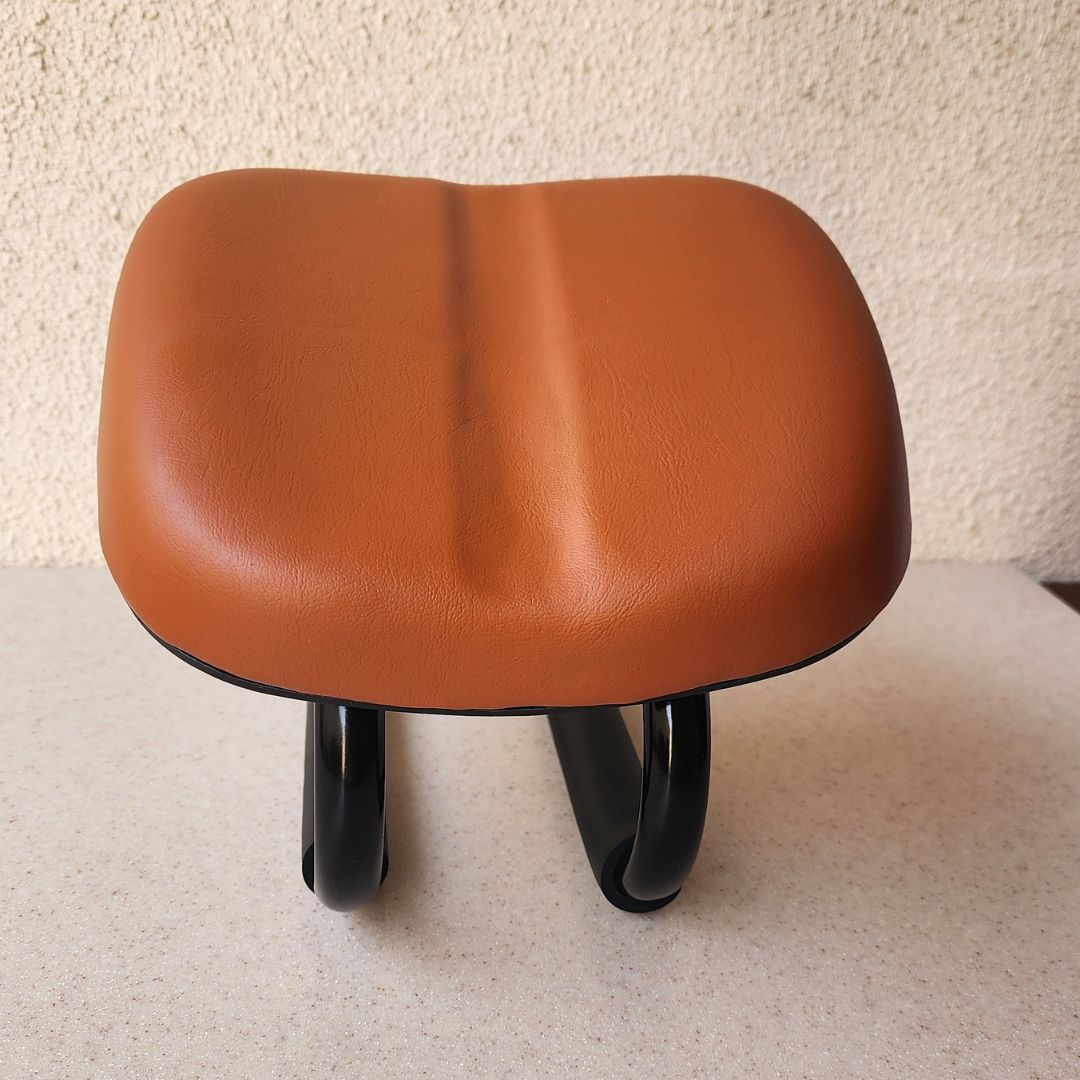 A Sujud Chair designed for praying Muslims, featuring a brown cushioned seat and a black metal frame with curved supports, placed against a plain background.