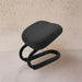 Black ergonomic chair on a light beige surface with a textured wall background