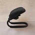 Black flexible phone stand on a light beige surface with a neutral background